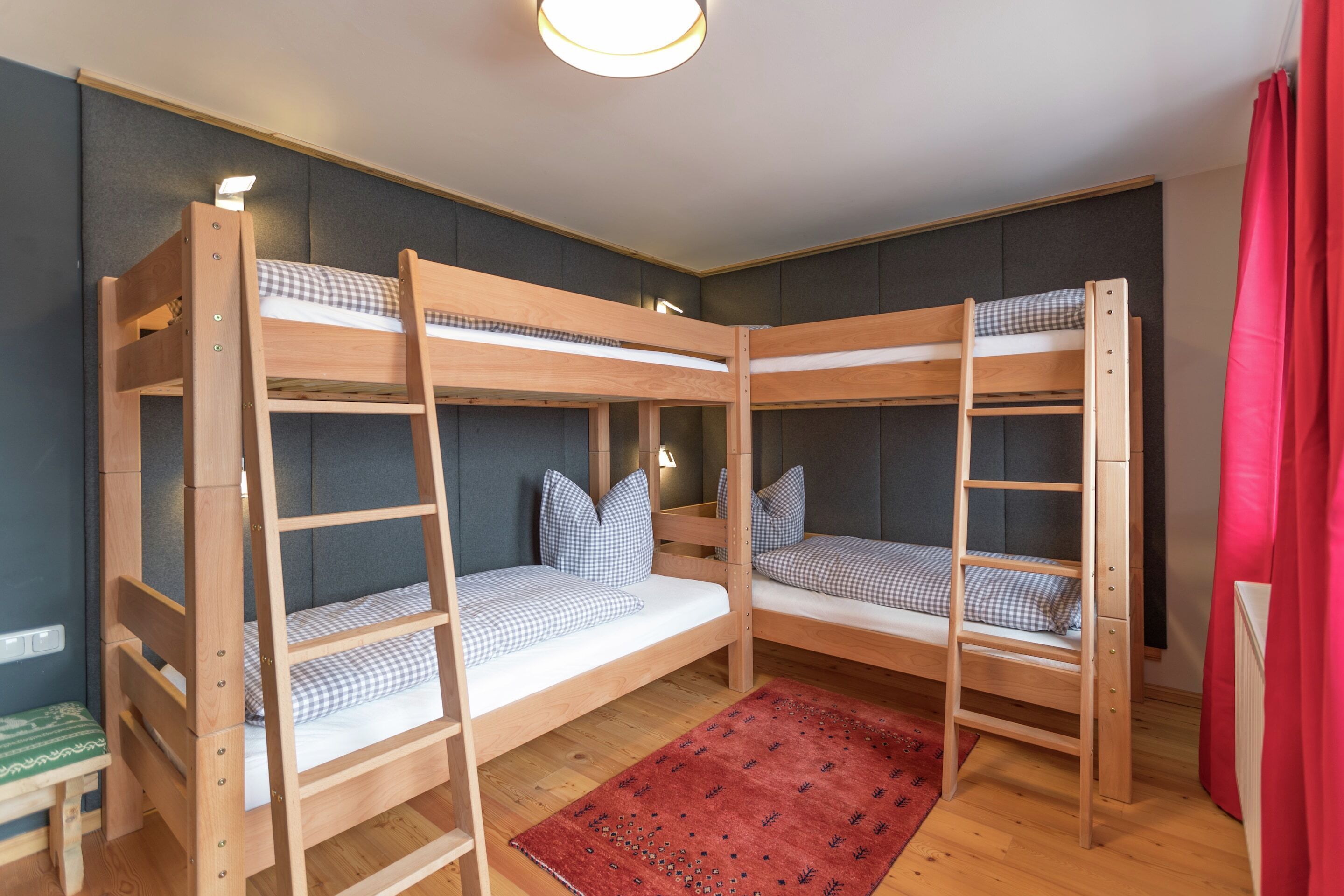 Ein Zimmer mit zwei Etagenbetten, einem roten Teppich und einem kleinen Tisch.