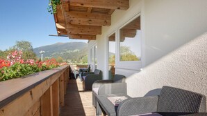 Eine Holzterrasse mit Korbmöbeln und einem Blumenbeet.