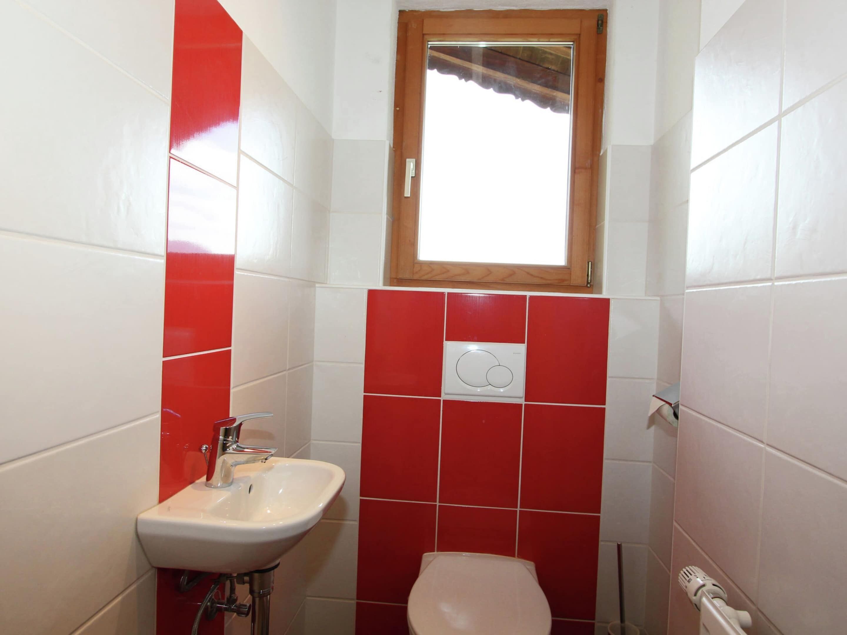 A small bathroom with a sink, toilet, and a window above the toilet.