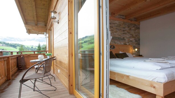 A wooden cabin with a balcony, a bed, and a dining area. - Stunning Holiday Home With Balcony, Ski Storage, Parking (Maria Alm am Steinernen Meer)