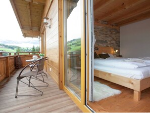 Una cabaña de madera con balcón, una cama y un comedor.