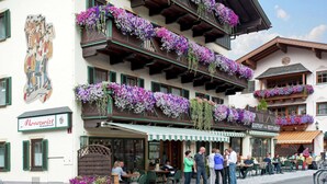 A traditional European building with multiple balconies adorned with flowers, a restaurant named "Gastrohof" on the ground floor, and a sign indicating a cafe restaurant. - Stunning Holiday Home With Balcony, Ski Storage, Parking (Maria Alm am Steinernen Meer)