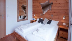 A wooden cabin bedroom with a large bed, two bedside tables, a mirror, and wall-mounted lights. - Stunning Holiday Home With Balcony, Ski Storage, Parking (Maria Alm am Steinernen Meer)