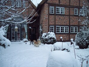 Ein schneebedecktes Backsteinhaus mit vielen Fenstern und einer sichtbaren Tür.