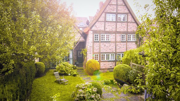 A traditional half-timbered house with a well-maintained garden, a bench, and a clear pathway leading to the entrance. - Altstadtzauber Lüneburg (Lueneburg)