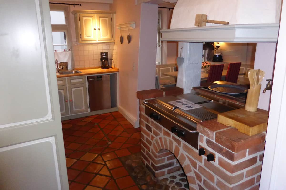 A compact kitchen with a brick oven, a coffee maker, and a sink.