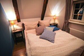 Ein Schlafzimmer mit einem Bett, zwei Nachttischen und einem Fenster mit Vorhängen.
