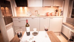 A kitchen with a wooden table, wine bottle, glasses, and a plate of chocolates. - Altstadtzauber Lüneburg (Lueneburg)