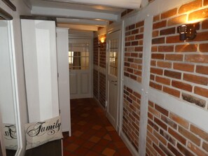 Ein Flur mit Backsteinwand, einer weißen Tür und einer Wandleuchte.
