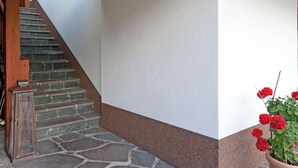 A staircase with stone steps and wooden railings, leading to a white wall with a brown baseboard.