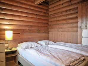 A wooden cabin-style room with a bed, a nightstand, and a lamp. - Chalet in Worgl Near Ski Lift (Woergl)