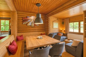 A cozy cabin interior with a wooden dining table, seating, and a large window. - Chalet in Worgl Near Ski Lift (Woergl)