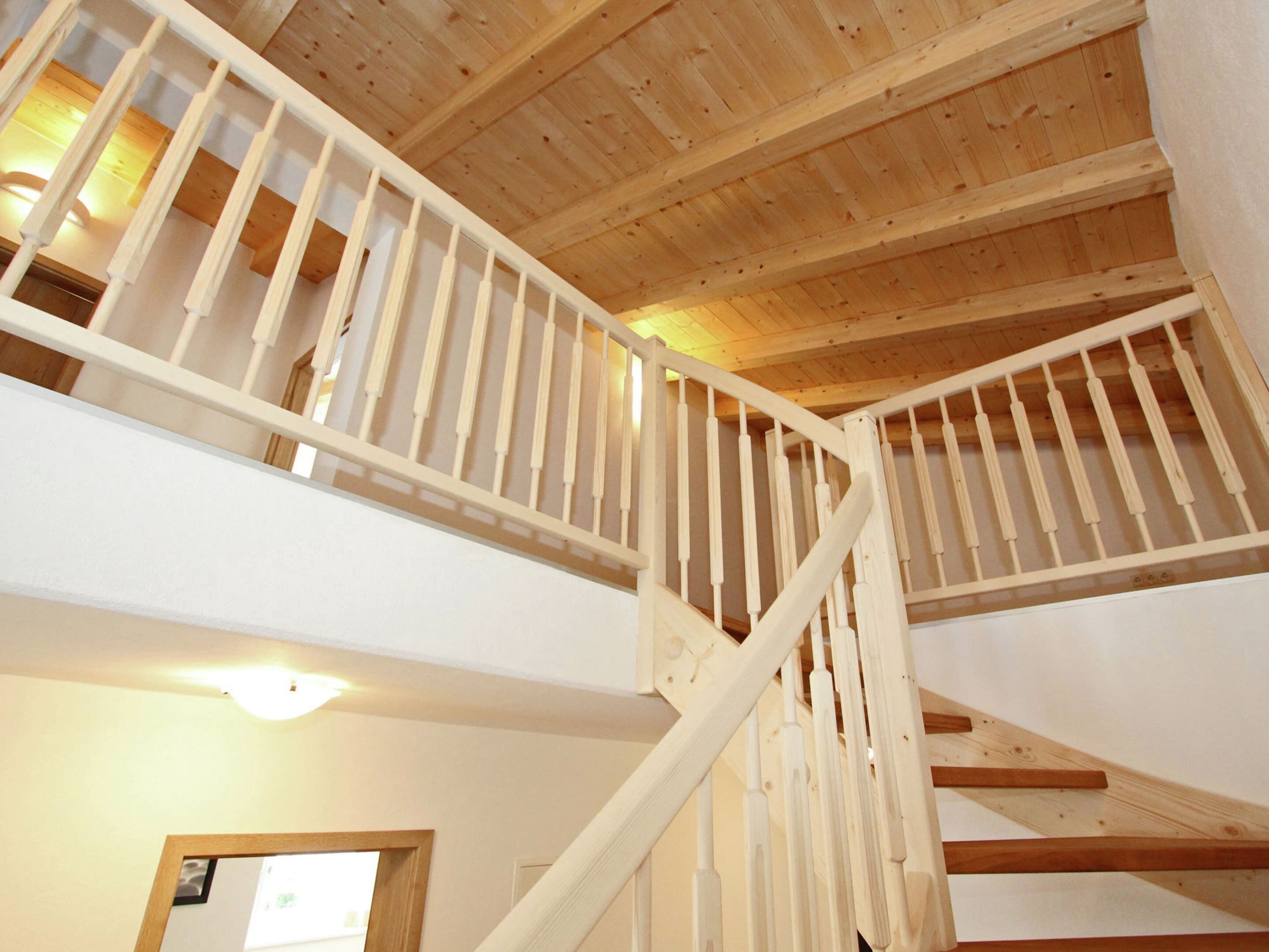 A wooden staircase with white railings leading to an upper floor.