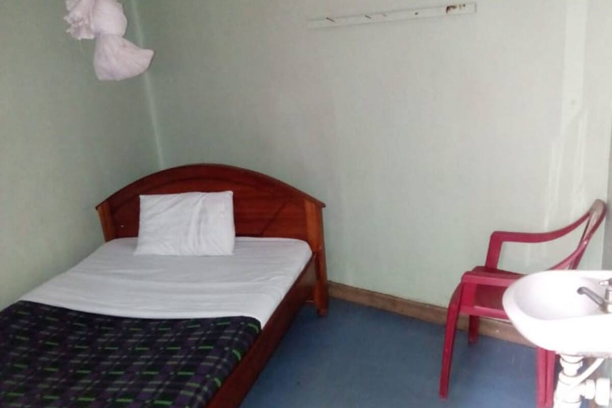 Um quarto com cama de madeira, uma cadeira vermelha e uma pia branca.
