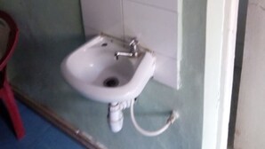 A bathroom with a white sink, a mirror, and a red chair. - Jupiter House (Kitengela)