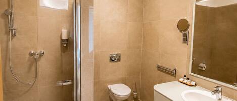 A modern bathroom with a glass-enclosed shower, a toilet, and a sink with a mirror.