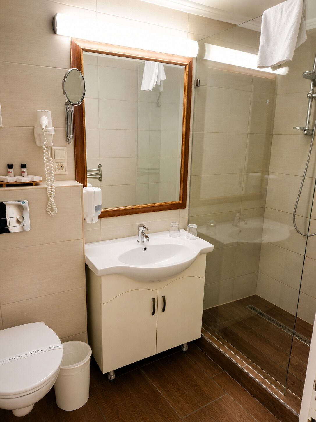A bathroom with a sink, mirror, toilet, and shower.