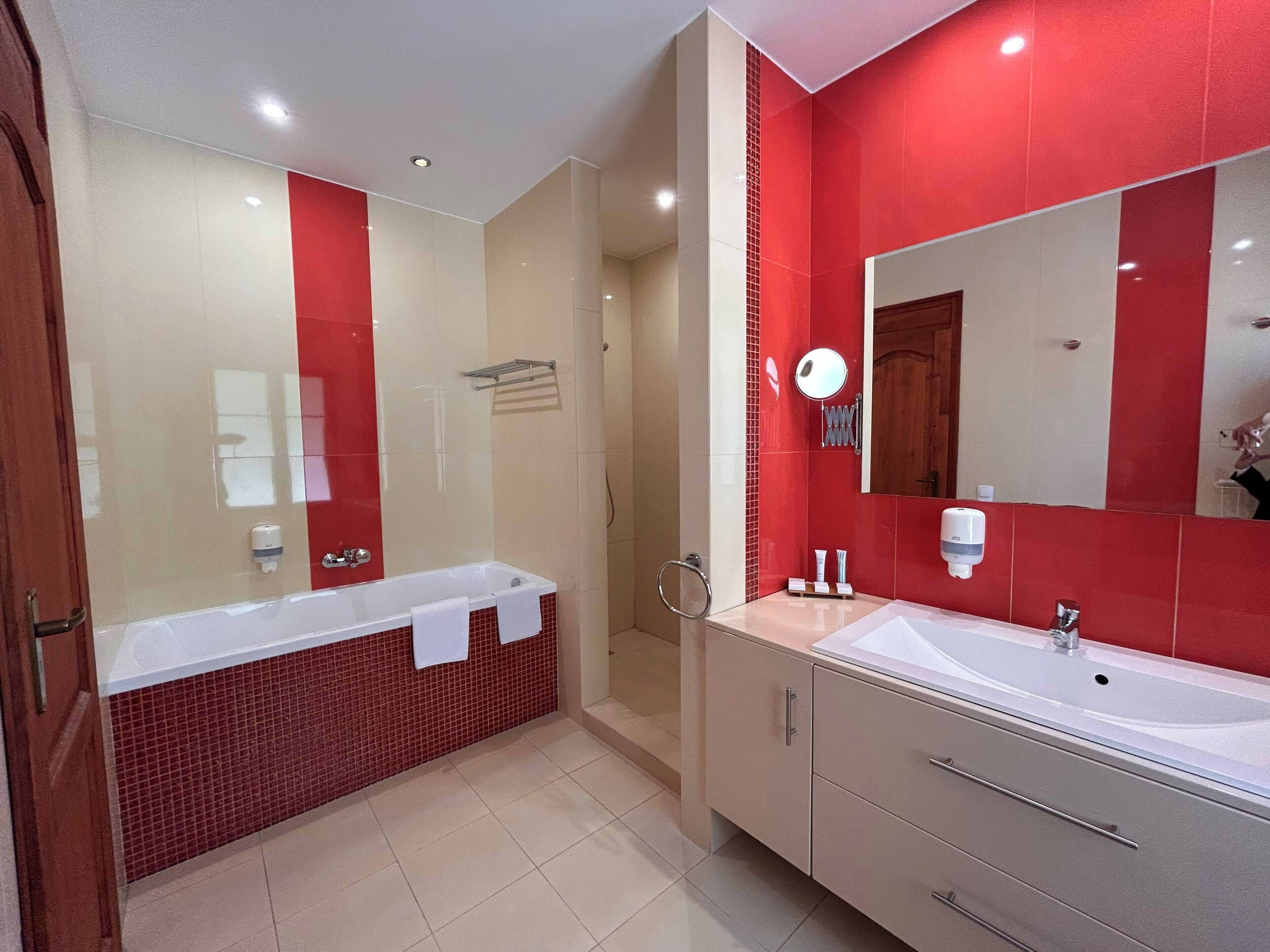 A modern bathroom with a bathtub, a large mirror, and a vanity with a sink.