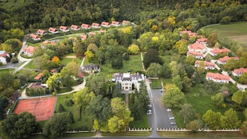 Vue aérienne d’un quartier résidentiel avec des maisons, un grand bâtiment central et de nombreux espaces verts environnants.