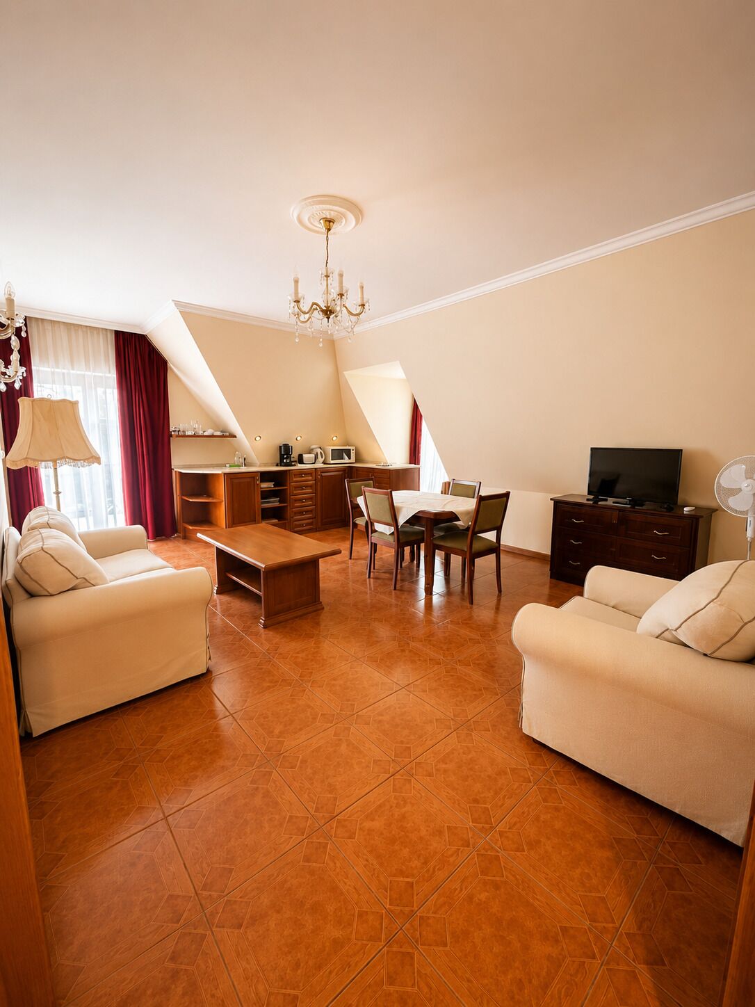 A spacious living room with a dining area, a TV, and a chandelier.