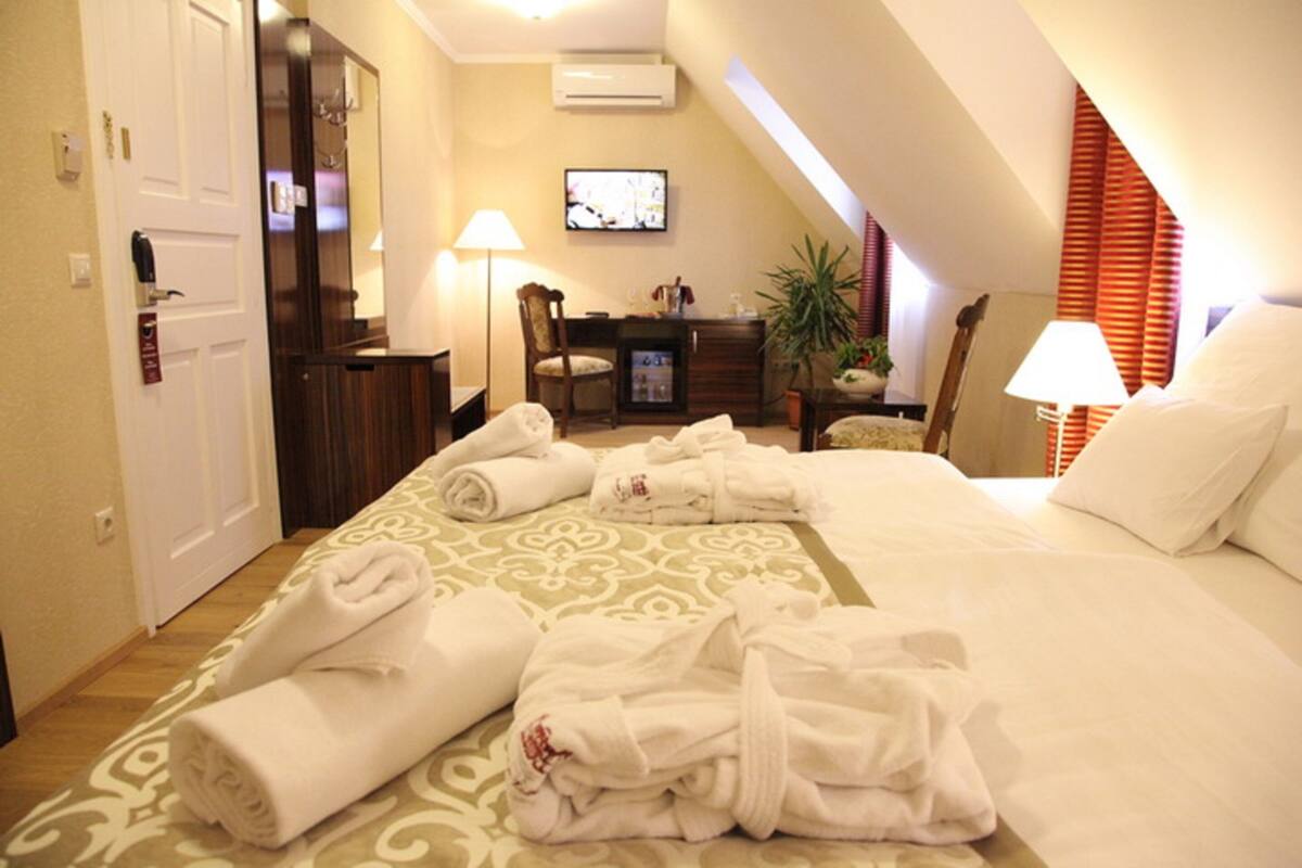 A hotel room with a bed, a desk, a chair, and a TV.