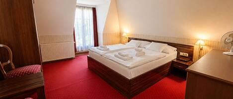 Una habitación de hotel con una cama grande, un escritorio, una silla y un radiador.