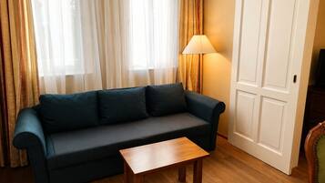 A living room with a dark green sofa, a wooden coffee table, a lamp, and a door.