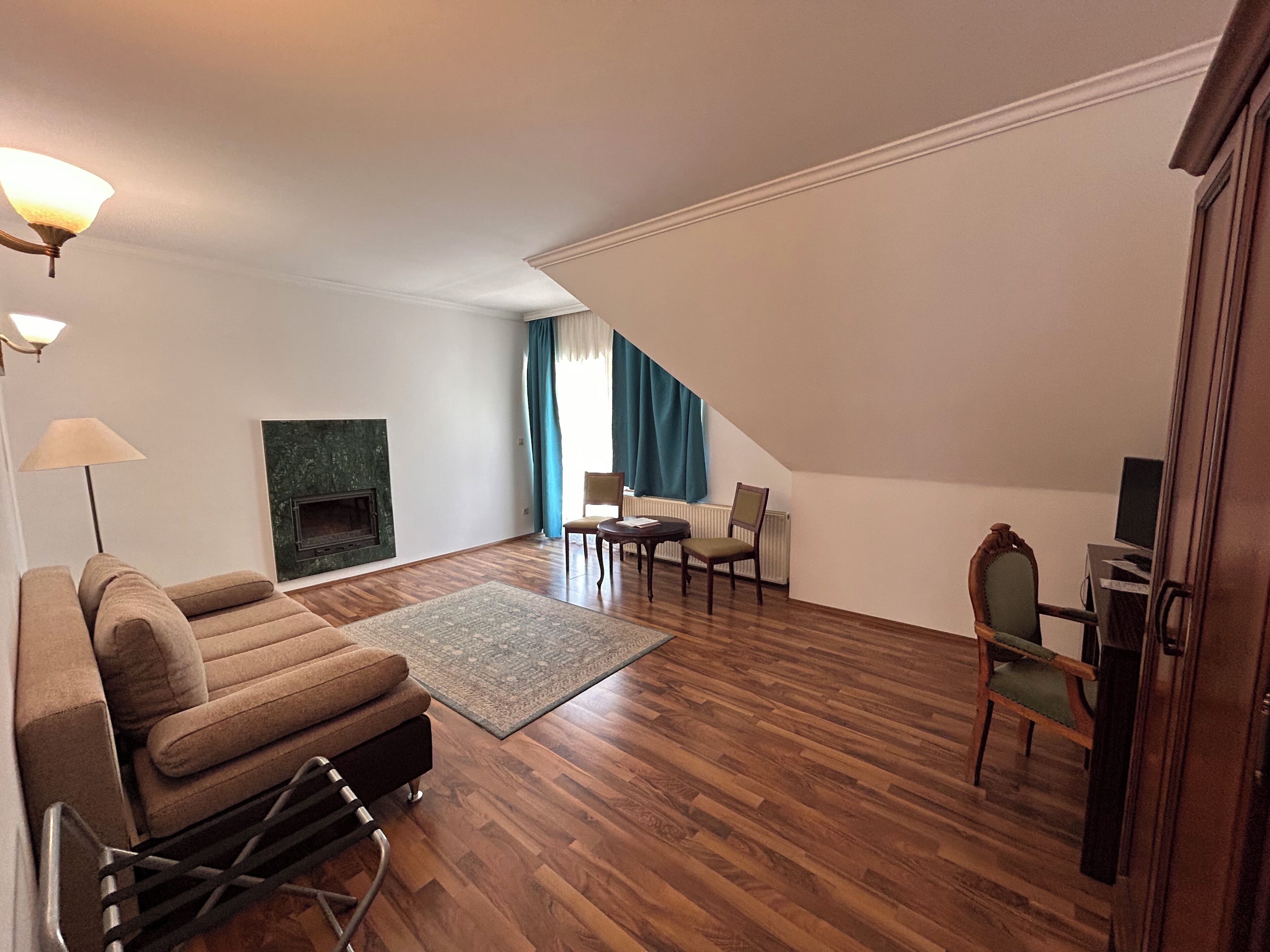 A living room with a fireplace, wooden flooring, a sofa, a coffee table, and a dining area with chairs.
