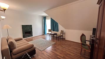Una sala de estar con chimenea, piso de madera, un sofá, una mesa de centro y un comedor con sillas.