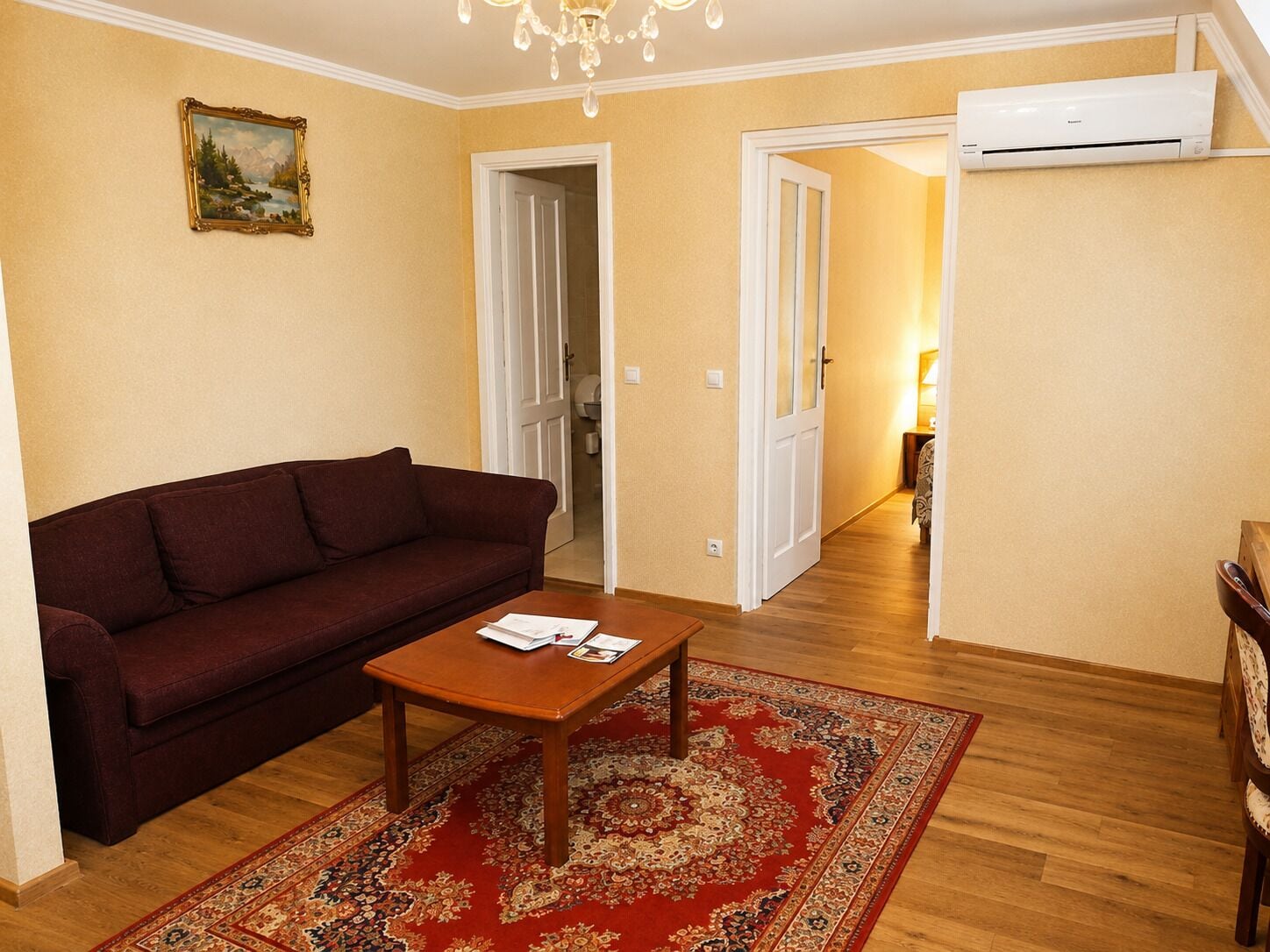 Een woonkamer met een bank, een salontafel, een tapijt met patroon en een airconditioning.