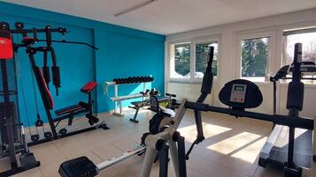 A gym with various exercise equipment, a bench, and dumbbells.