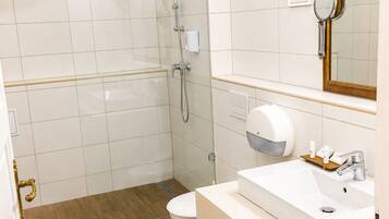 A modern bathroom with a shower, toilet, sink, and a mirror.