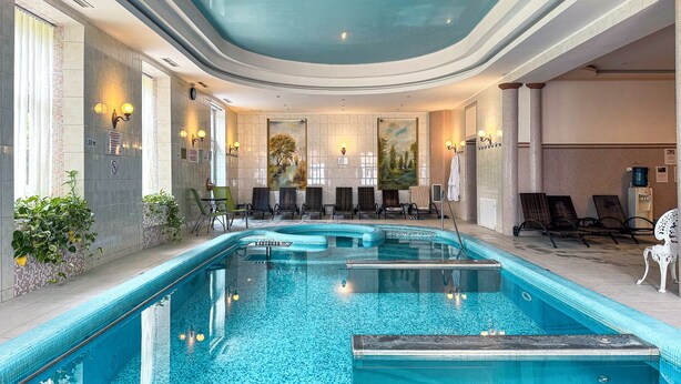 A large indoor pool with multiple lanes, lounge chairs, and a tiled wall with artwork. - Batthyány Kastélyszálló (Zalacsany)
