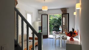 Un área de estar amplia con una mesa de comedor, un sofá y una escalera que lleva a otra habitación.