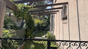Una entrada protegida con un portón de hierro forjado y una estructura de pérgola.