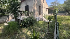 Un pequeño edificio de una sola planta con tejado de tejas, un balcón con barandilla de metal y una pequeña escalera que lleva a la entrada.