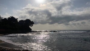 Una playa con olas, cielo despejado y sol.