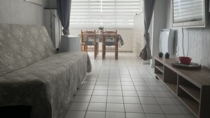 A room with a bed, a dining table with chairs, a ceiling fan, and a TV mounted on the wall. - Sea view apartment in SETE (Sète)