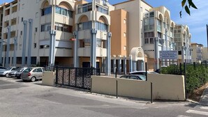 A multi-story hotel with a beige facade, balconies, and a gated parking area. - Sea view apartment in SETE (Sète)