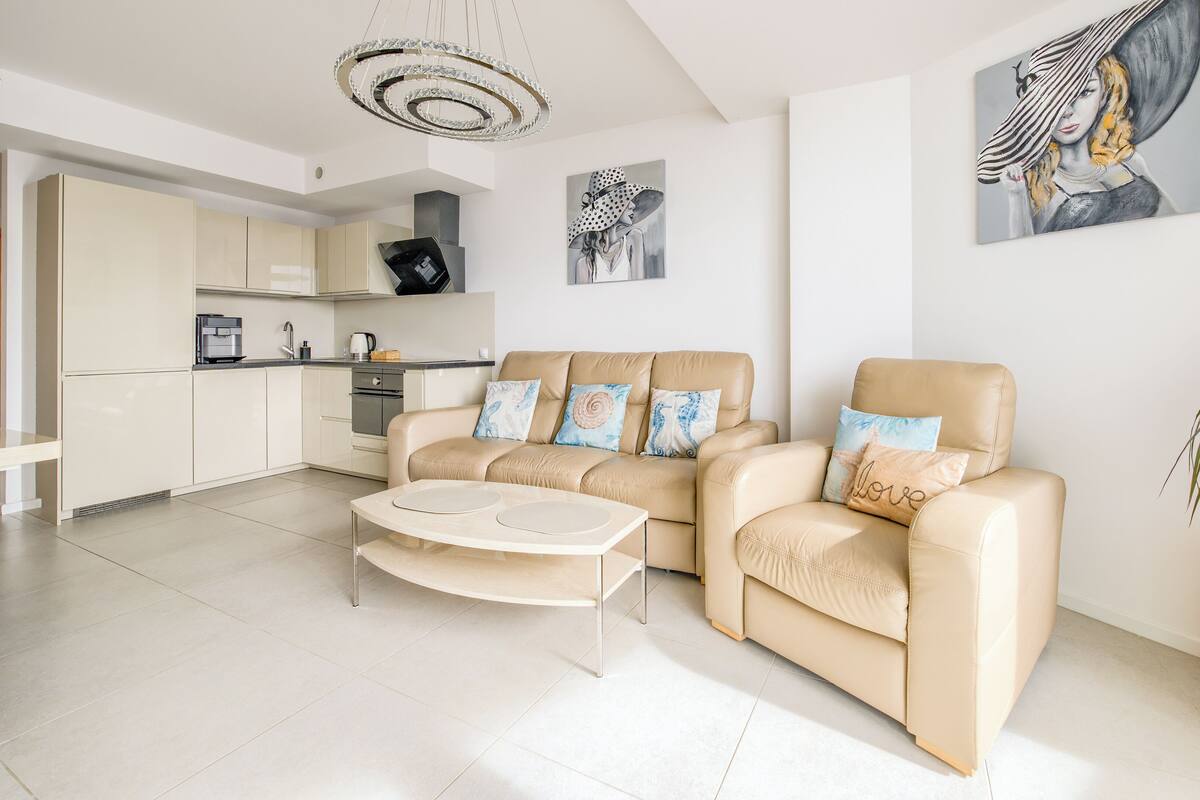 A modern living room with a beige sofa, a coffee table, and a potted plant.