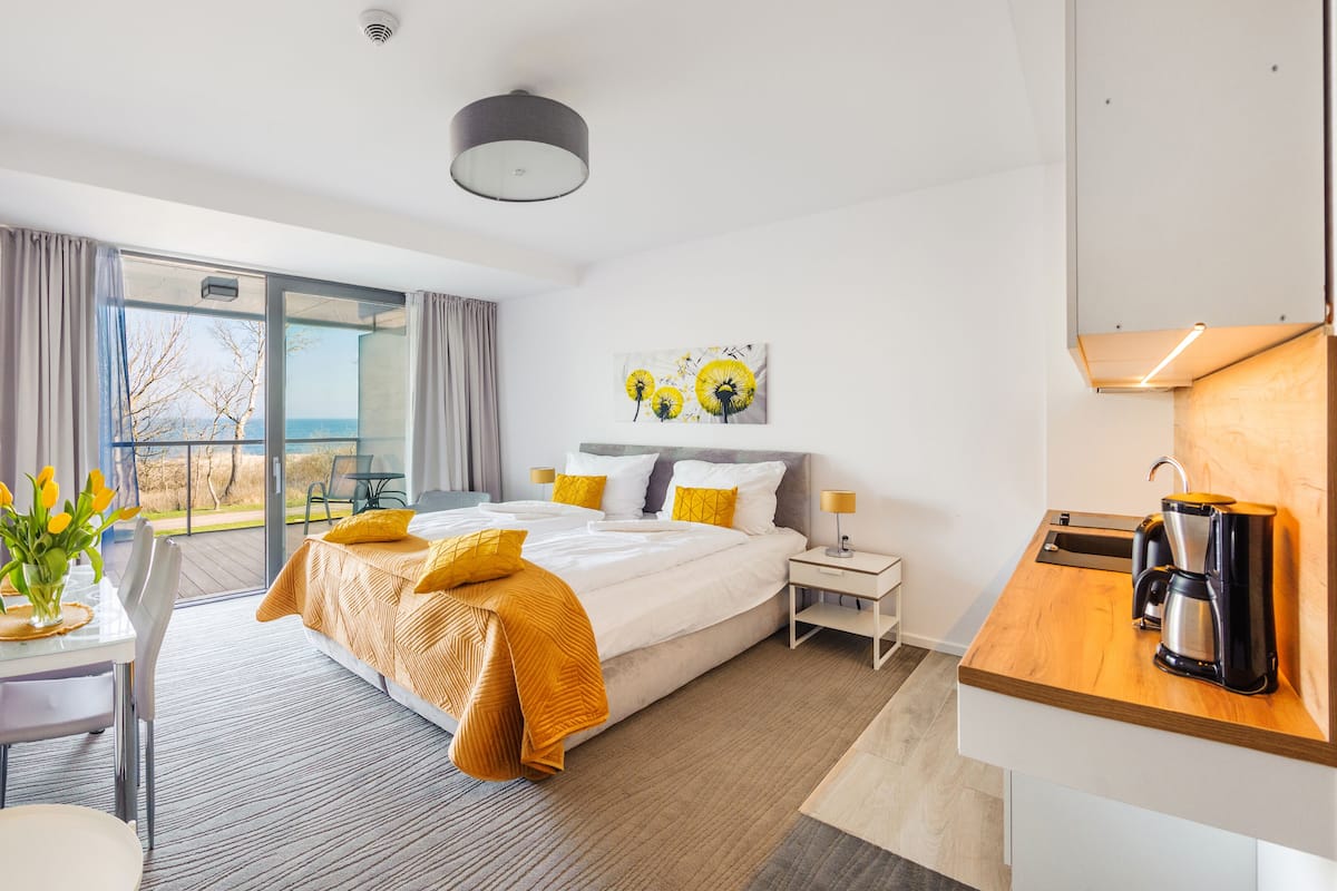 A hotel room with a large bed, a desk, a coffee maker, and a view of the outdoors.