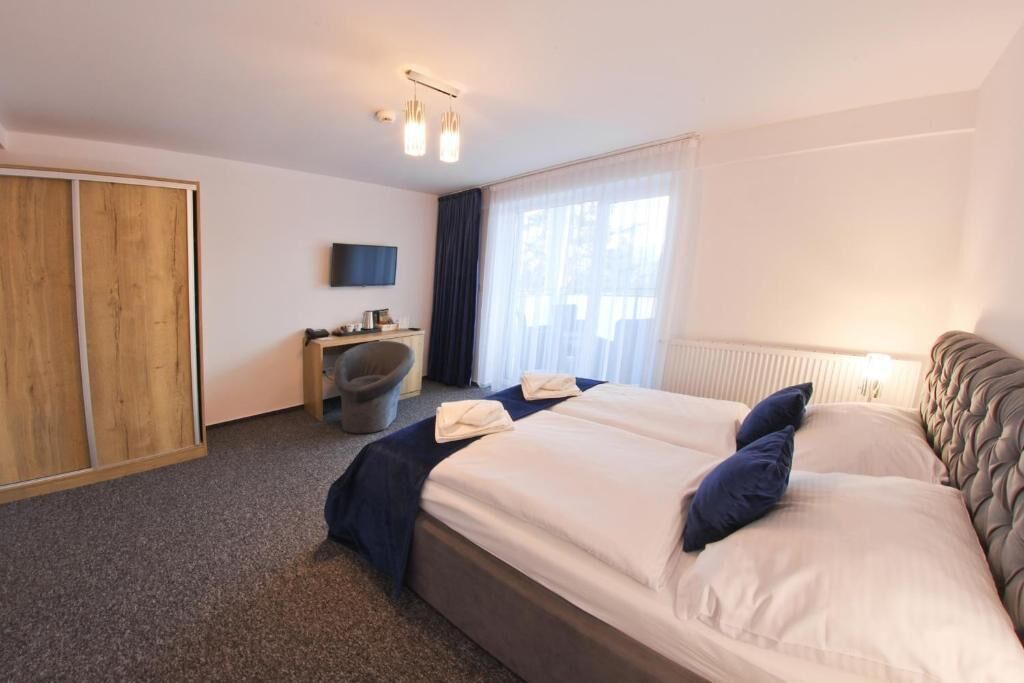 A hotel room with a large bed, a desk, a chair, and a television.