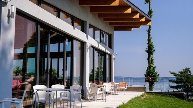 A modern building with large windows and outdoor seating. - Hotel Prístav (Trstená)