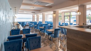 A restaurant with blue upholstered chairs, wooden tables, and a marble floor. - Hotel Prístav (Trstená)