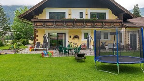 Ein zweistöckiges Haus mit Balkon, Trampolin und Gartenmöbeln.