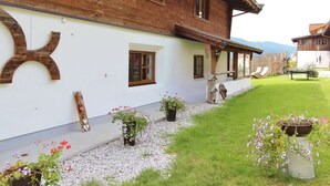 A wooden chalet with a white exterior, a gravel pathway, and potted plants.