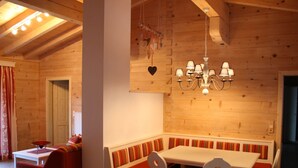 A cozy wooden interior with a dining area featuring a white table and red-striped benches.