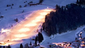 Une montagne enneigée, avec une piste de ski et un petit village à ses pieds.