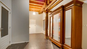 Ein Flur mit Holztüren, Fliesenboden und einer Decke mit freiliegenden Balken.