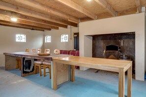 Una habitación rústica con vigas de madera a la vista, una mesa grande de madera y una chimenea.